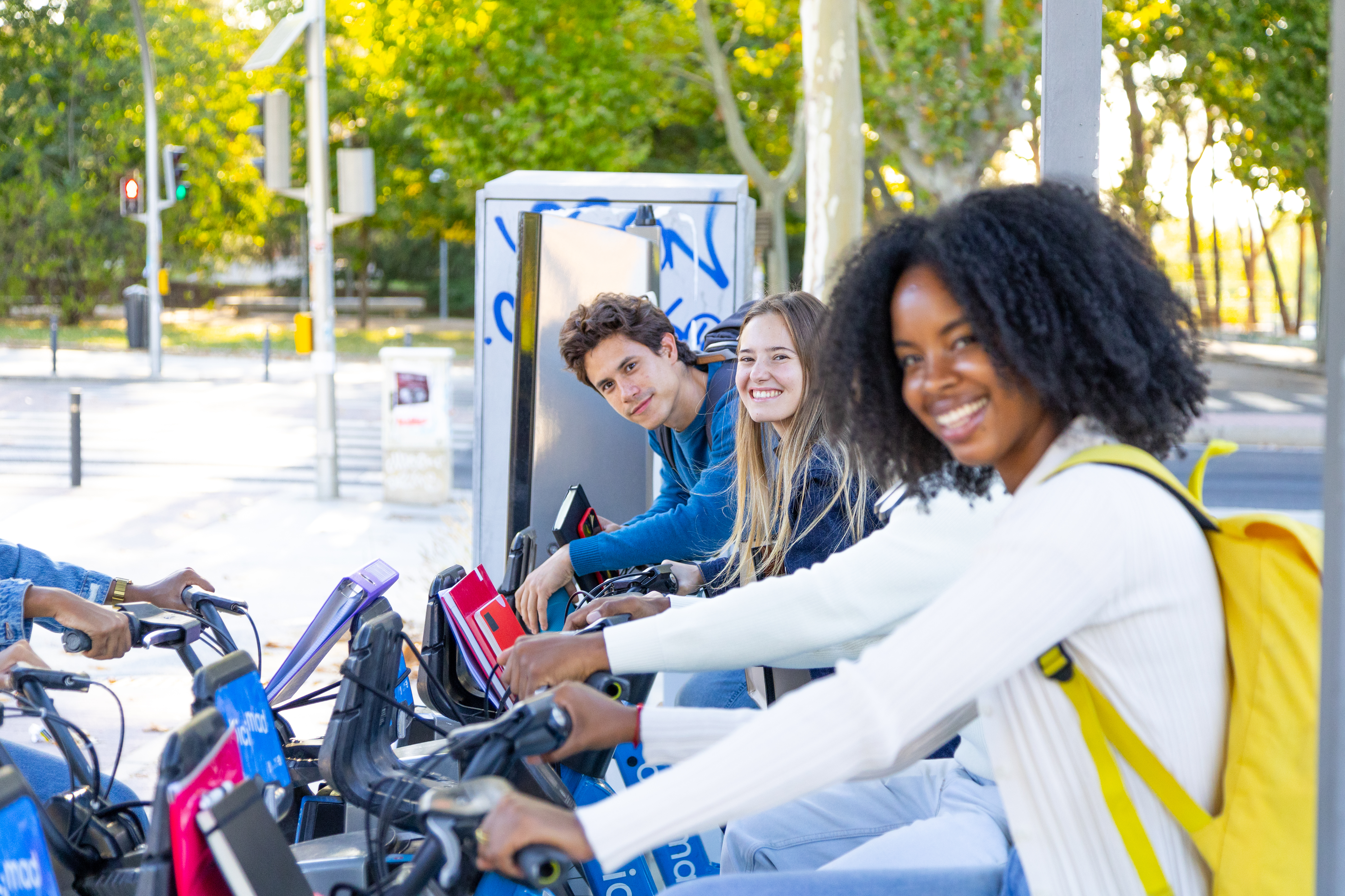 Diverse friends smiling while renting bikes at an urban station, promoting sustainable city transport and youth eco tourism